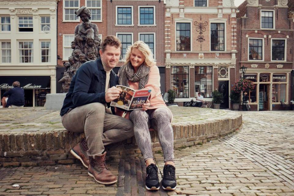 man en vrouw kijken op een gids van een stadswandeling
